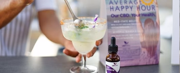 Cocktail glass with a spoon and purple-striped straw, a dropper bottle labeled 'CBD 3000mg', and a blurred sign reading 'AVERAGE HAPPY HOUR Our CBD. Your Health.'