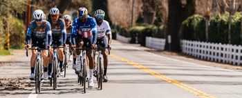 A group of cyclists from L39ION of Los Angeles riding on a road.