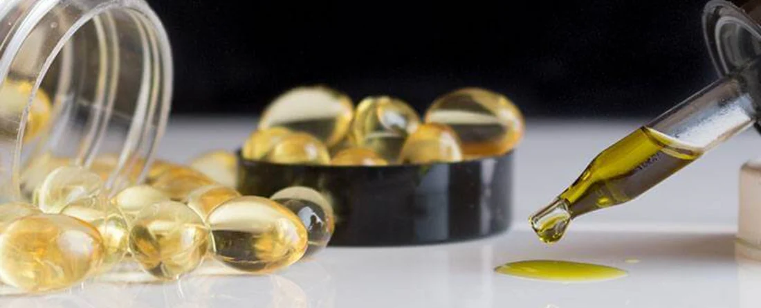 CBD oil capsules and dropper on a surface