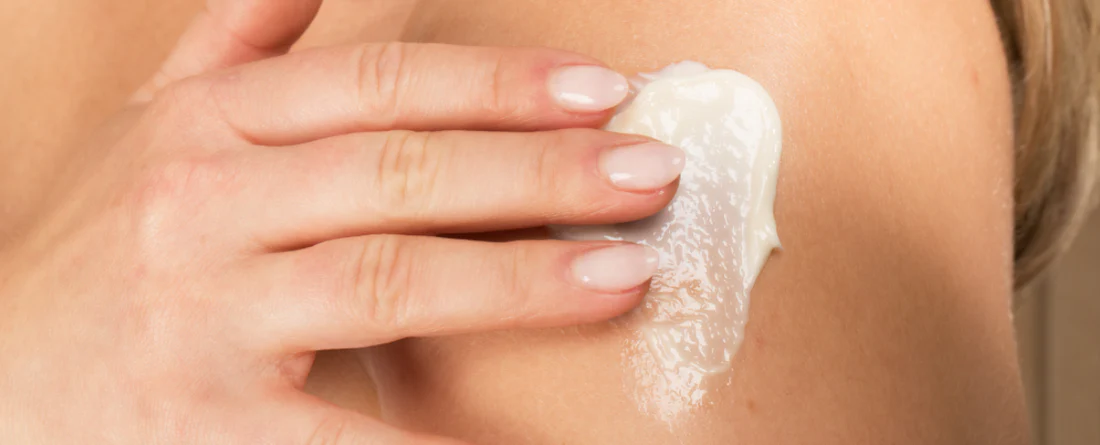 A person applying a CBD topical cream on their shoulder for post workout recovery.