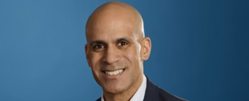 Medterra’s new CEO smiling in a suit against a blue studio background