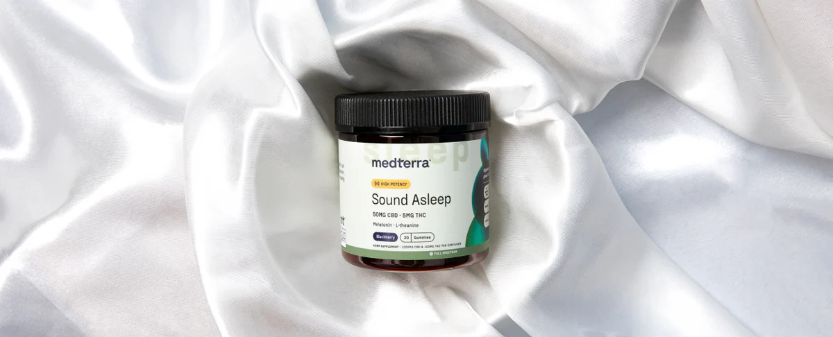 Front view of Medterra Sound Asleep gummies jar showing black screw-top lid and product label on white silky fabric