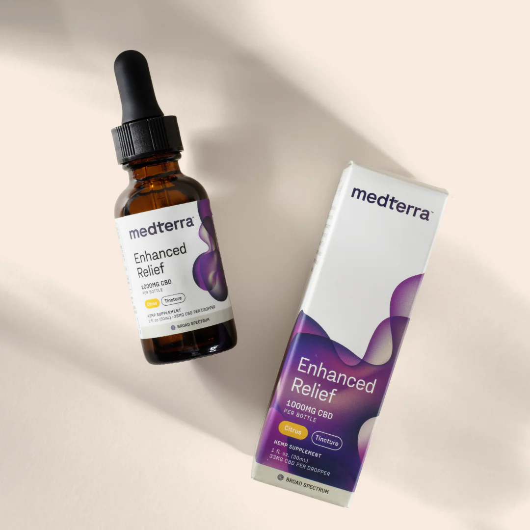 Angled overhead of Medterra Enhanced Relief broad spectrum CBD tincture bottle and box showing 1000mg CBD and Citrus on beige background