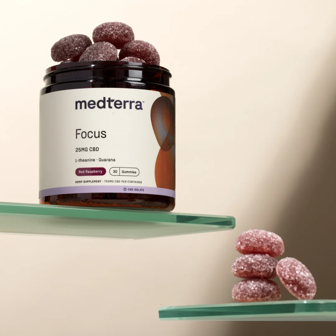 Front view of Focus CBD Gummies jar, label 25MG CBD L-theanine Guarana, sugar-coated red raspberry gummies on glass shelves