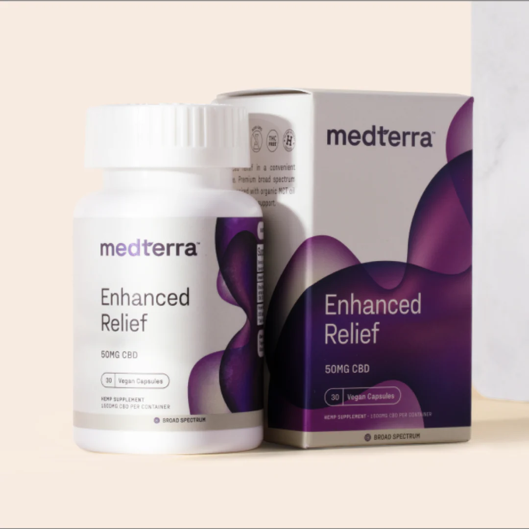 A bottle and box of Medterra Enhanced Relief Broad Spectrum Capsules, showcasing "50MG CBD" and "Vegan Capsules." The white container with a purple abstract design prominently features the brand name "Medterra." This product utilizes Broad Spectrum CBD. The background is a neutral beige.