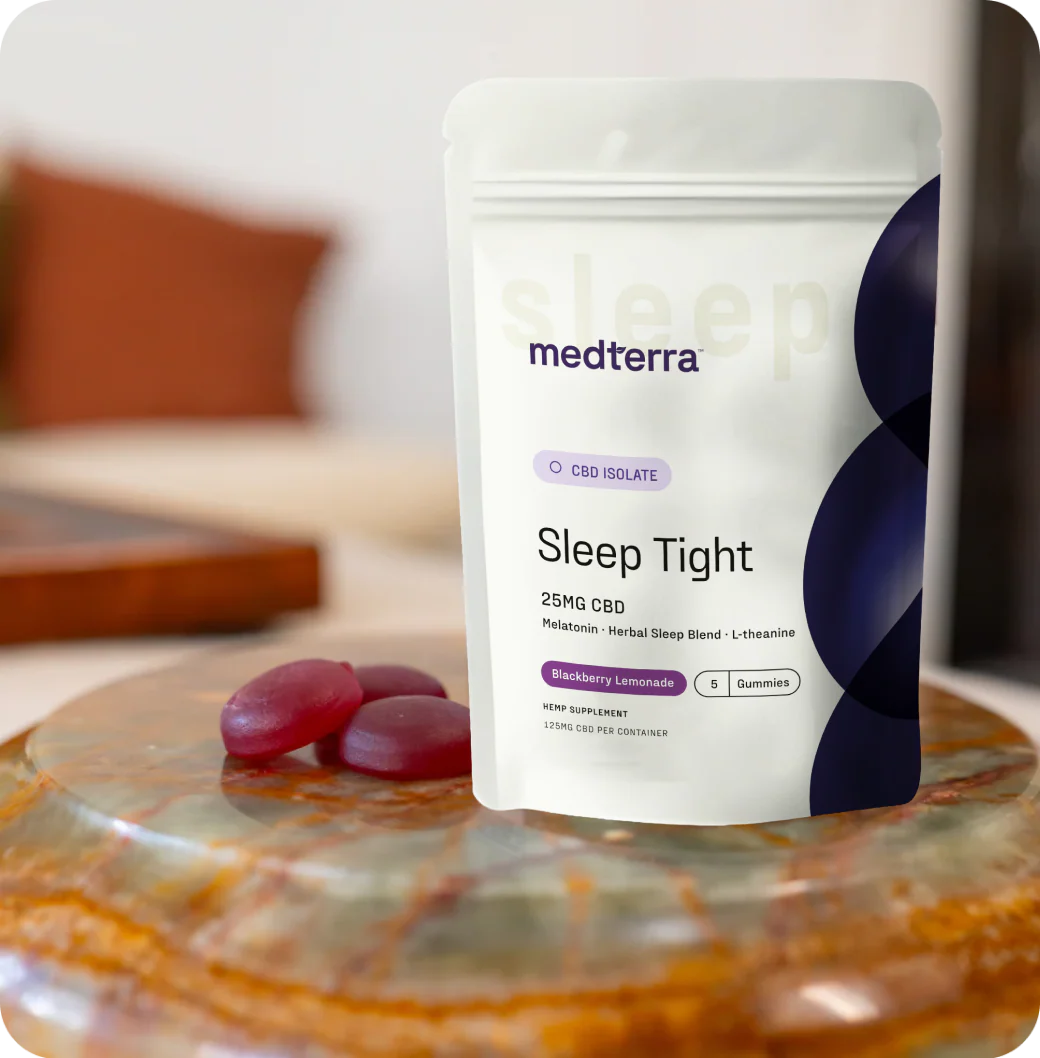 Front view of Medterra Sleep Tight pouch showing 25mg CBD label with three purple gummies on a marble table and blurred background