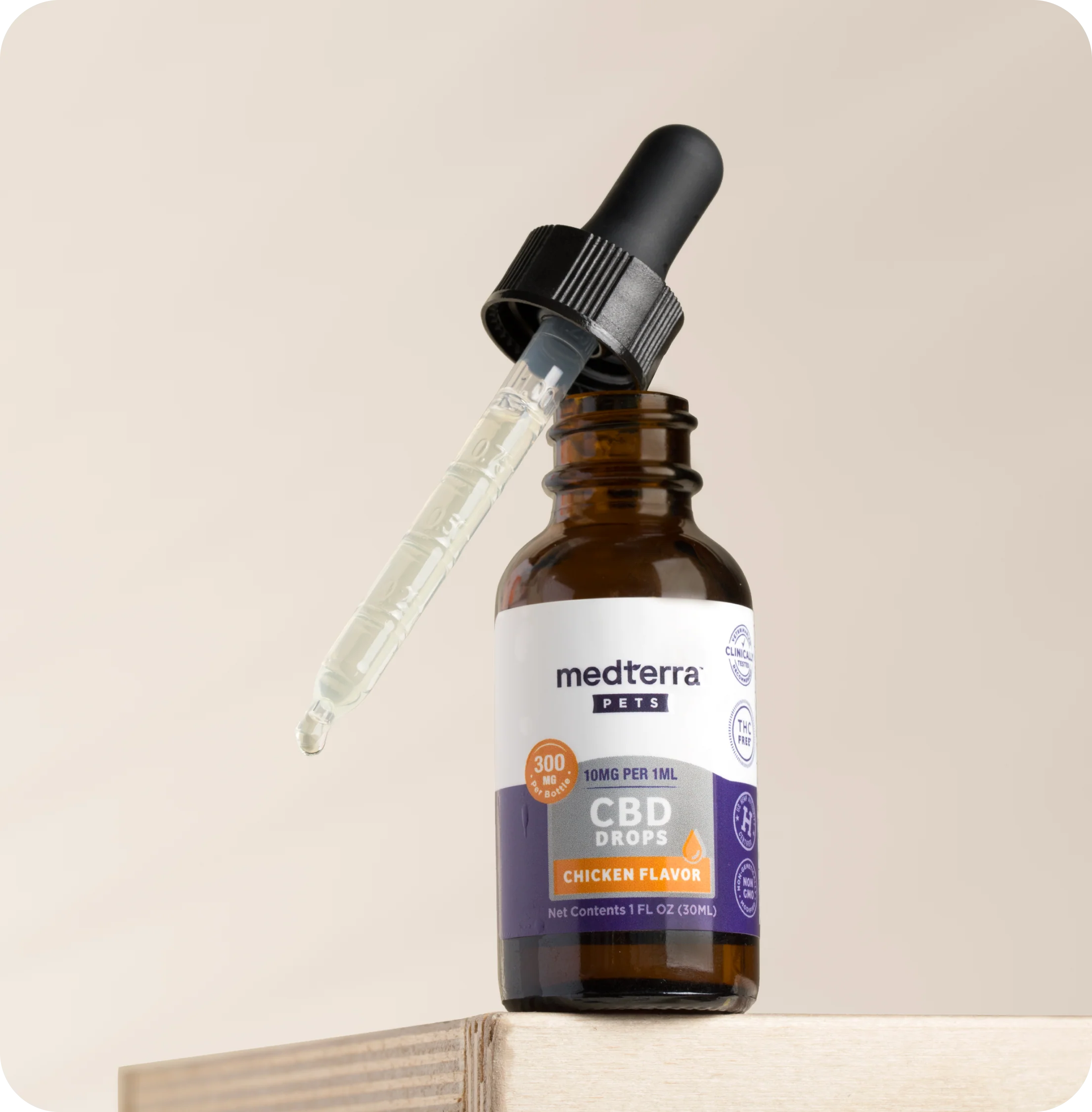 Close-up of Medterra Pets CBD dropper bottle showing chicken flavor label and 10 mg per 1 mL dose markings on a beige background