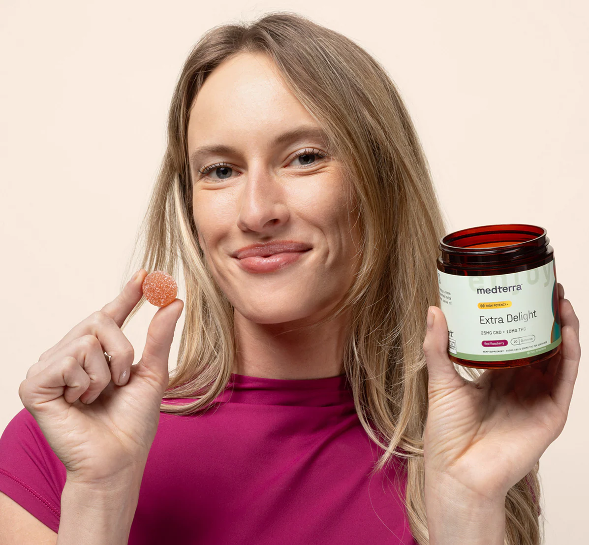 Front view of Extra Delight high-potency gummy jar held by a woman holding a red raspberry gummy