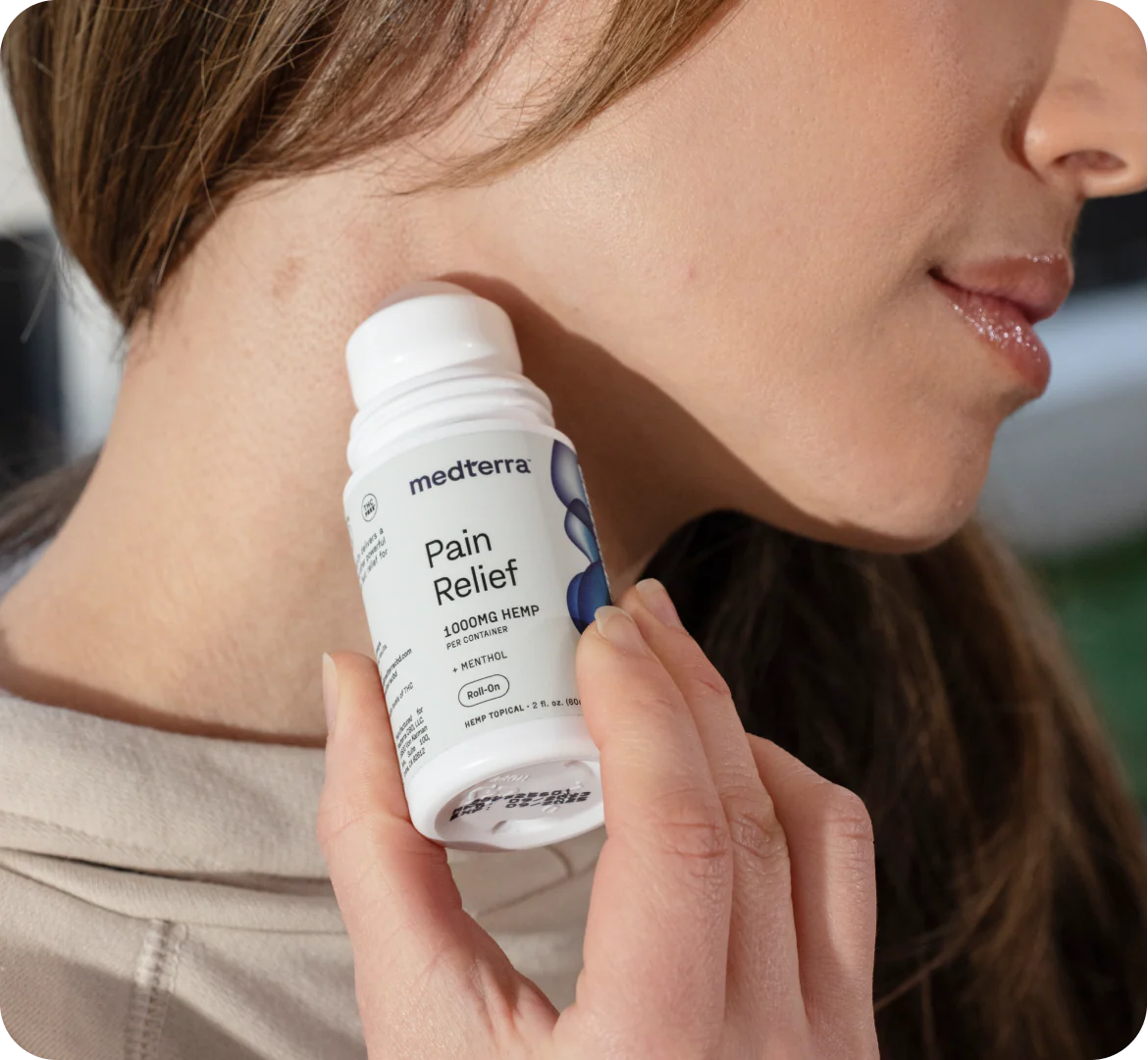 Close-up of Medterra Pain Relief CBD roll-on showing Pain Relief label and roll-on applicator against a person's neck