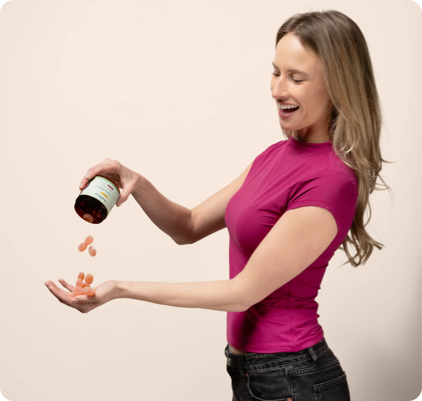 A smiling woman in a magenta shirt pours Medterra Extra Delight 10mg THC Gummies from a bottle into her hand against a plain light background.