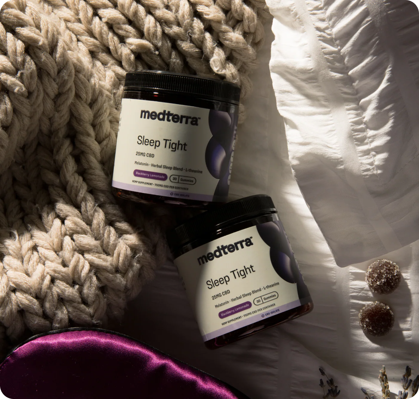 Angled top view of two Medterra Sleep Tight jars showing 25MG CBD and melatonin on a knitted blanket and white bedding